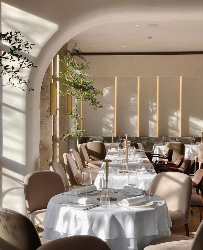 An arched dining room with round tables dressed in white linen