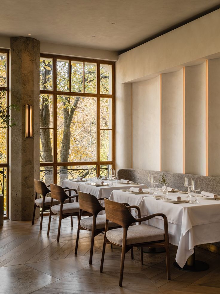 A dining room with white linen tables and tall windows