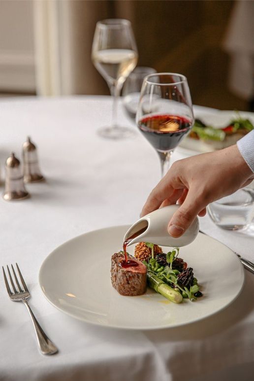 A chef finishing a plate with sauce at the table